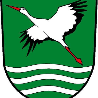 Auf grünen Hintergrund: Storch im Flug, darunter drei weiße gewellte Linien