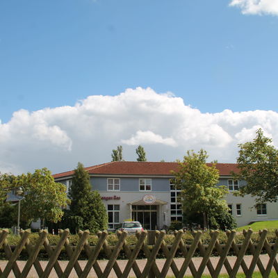 Blick auf das Haus am Langen See über einen Jägerzaum hinweg.