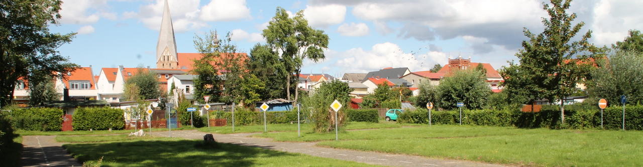 Bild vergr&ouml;&szlig;ern: Im Vordegrund ist der Verkehrsgarten mit seinen Verkehrsschildern und Wegen  zu sehen. Im Hintergrund sind Häuser der Altstadt Bützow abgebildet.