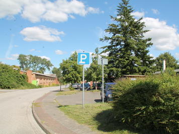 Kleiner Parkplatz in Zentrumnähe mit schattenspendenden Bäumen.