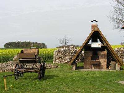 Bild vergr&ouml;&szlig;ern: Außenanlage mit Backofen, im Hintergrund liegt ein Rapsfeld.